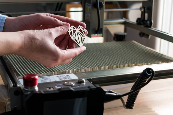 Lazer oyma ve kesme, kesilmiş tahta kalp örneği tutan bir kadın.