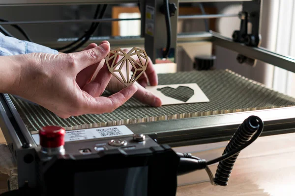 Lazer oyma ve kesme, kesilmiş tahta kalp örneği tutan bir kadın.