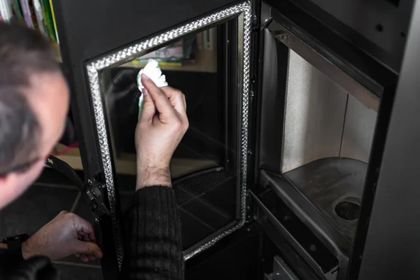 Bardağın üzerindeki külleri temizleyen bir adam ya da kağıt havlu ve sıcak suyla odun sobası.