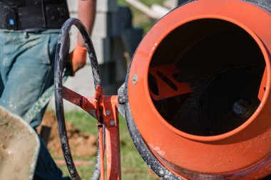 Duvarcı inşaat alanında duvar örmek için beton karıştırıcı ile beton hazırlıyor.