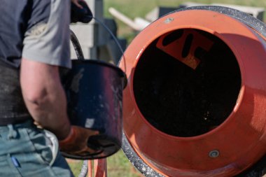 Duvarcı inşaat alanında duvar örmek için beton karıştırıcı ile beton hazırlıyor.