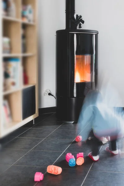 Pellet stove with a child playing safely in front, with flames and library
