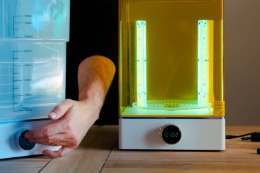 Adam UV ışığını kullanarak 3 boyutlu reçine yazıcısı için bir yıkama ve tedavi makinesini ayarlıyor