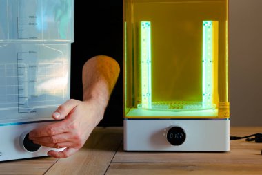 Adam UV ışığını kullanarak 3 boyutlu reçine yazıcısı için bir yıkama ve tedavi makinesini ayarlıyor