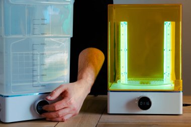 Adam UV ışığını kullanarak 3 boyutlu reçine yazıcısı için bir yıkama ve tedavi makinesini ayarlıyor