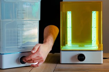 Adam UV ışığını kullanarak 3 boyutlu reçine yazıcısı için bir yıkama ve tedavi makinesini ayarlıyor