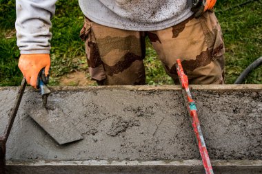 İnşaat alanında duvar örmek için beton döşeyen tuğla ustası.