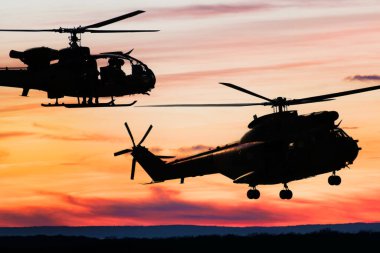 Gün batımında savaş helikopterlerinin silueti gökyüzünde, ceylan ve puma tarafı görünümü, hava ulaşımı