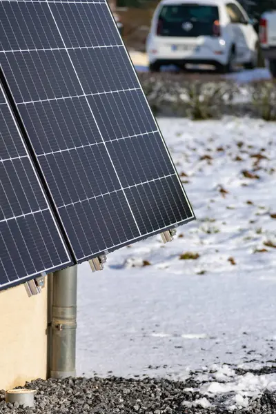 Solar panels with snow on ground on a well-exposed wall of an individual house, making savings following the energy crisis, eco-citizen gesture, green energy