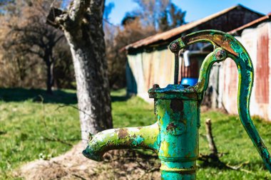 Old hand water pump on a well in the garden, watering and saving water, rural environnement