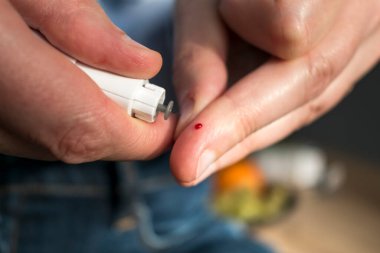 Kan şekeri seviyesini glukometreyle ölçmek için parmağını delen kadın kan şekerini diyabet için test ediyor.