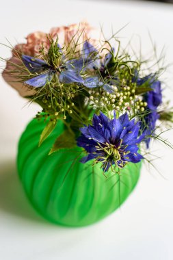 Nigella çiçeği ve gül reçineyle basılmış küçük bir vazoda