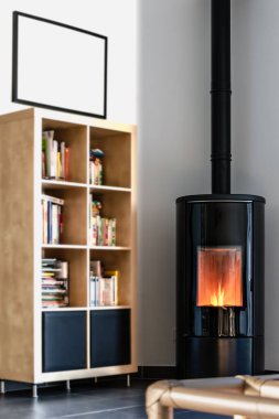 Modern yerli pelet sobası, alevli granüller ve kütüphane.