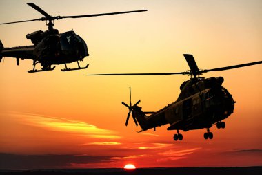 Gün batımında savaş helikopterlerinin silueti gökyüzünde, ceylan ve puma tarafı görünümü, hava ulaşımı