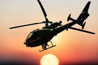 Gün batımında savaş helikopterinin silueti gökyüzünde, ceylanın yan görünüşü, hava ulaşımı