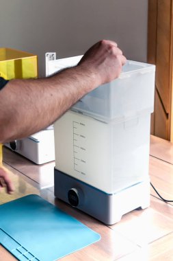 3 boyutlu şeffaf bir reçine nesnesini temizlemek için çamaşır makinesi kullanan bir adam