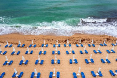 Mavi şezlonglar, şemsiyeler ve turkuaz deniz manzaralı harika bir sahil manzarası..