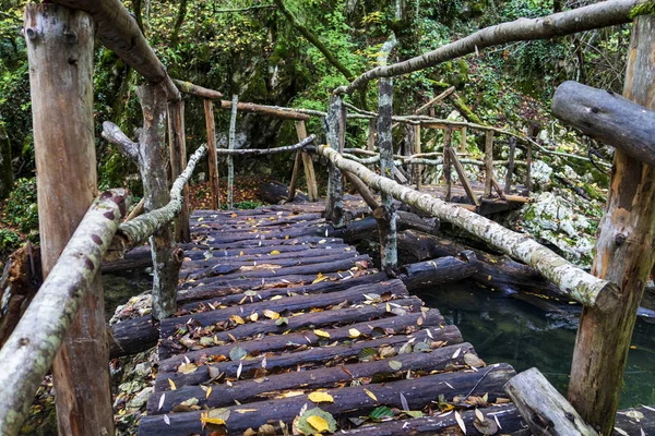 Wooden handmade bridge in the forest over river