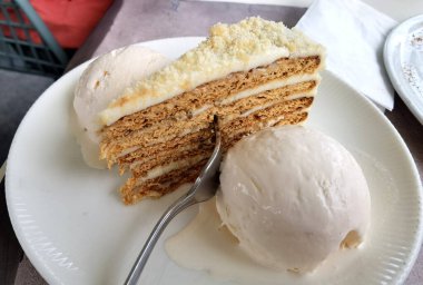 Hassas bir parça pasta ve dondurmayı çatalla bir tabağa koy.