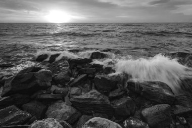 Denizin üzerinde inanılmaz bir gökyüzü ve kayalık deniz kıyısının siyah beyaz dalgaları..