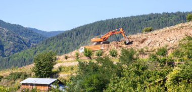 Kazı makinesi kamyona kazı yapıyor. İnşaat alanında çalışan ağır inşaat malzemeleri..