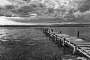 Heyecanlı bulutlar gökyüzüne ve göle karşı ahşap iskelede 