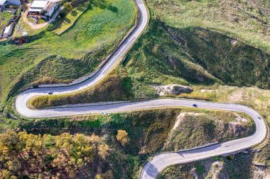 Dağ zirvesinin altında eğri bir dağ yolunun havadan çekilmiş fotoğrafı..
