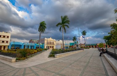 Bayamo, Küba - 12 Aralık 2018: Günbatımında renkli binaların olduğu bir kasaba meydanında canlı bir sahne, Bayamo, Küba