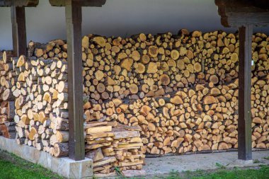 Büyük bir odun yığını düzgünce kaplanmış bir alanın altına yerleştirilmiş.