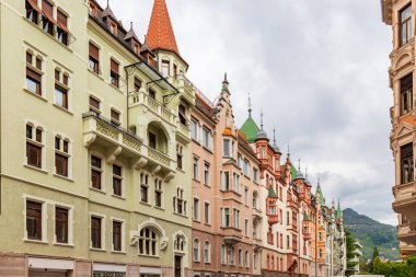 Bir sıra büyüleyici, renkli Avrupa binaları eşsiz mimarisi ve dekoratif çatıları olan, bulutlu gökyüzüne karşı.