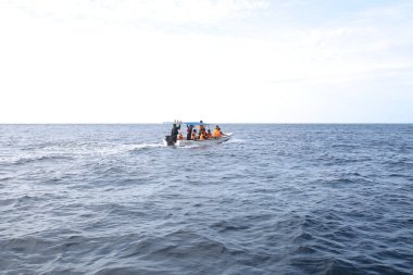 Bir grup turist denizdeki mavi teknede.