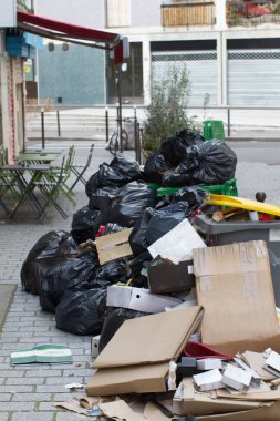 Kirli karton yığını ve şehirdeki kafe masalarının yakınındaki kaldırımda patlayan plastik çöp torbaları.