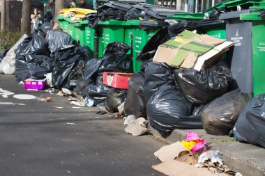 Paris, Fransa 'da sokaklara ve bisiklet yollarına yığılmış plastik, karton ve çöplerle dolu çöp poşetleri ve çöp konteynerleri.