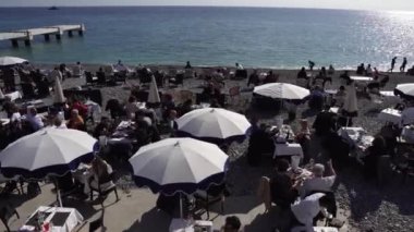 People sit on the street on the beach in a restaurant near the French Riviera in the city of Nice. Beach panorama. People chat and dine in a restaurant