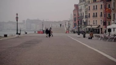 Venice is covered with fog. The capital of the region of the same name in northern Italy. Channel movement. City street on the water. People walking. Panorama of the city in the fog