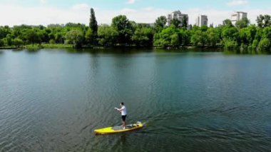 Kuzey Avrupa 'daki güzel bir gölde SUP sörfü yapan genç bir adamın insansız hava aracı görüntüsü. Sumy şehrinde Ukrayna 'da bir gölde jipli bir adam yüzüyor.