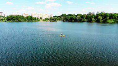 Kuzey Avrupa 'daki güzel bir gölde SUP sörfü yapan genç bir adamın insansız hava aracı görüntüsü. Sumy şehrinde Ukrayna 'da bir gölde jipli bir adam yüzüyor.
