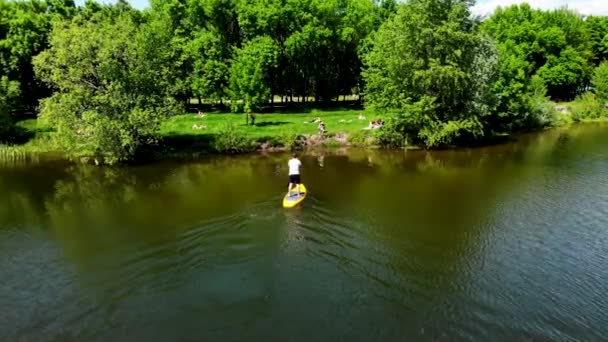 在北欧一个美丽的湖面上 看到一个年轻人划着一个苏打水冲浪板 在乌克兰苏美市的一个湖面上漂浮着一个拿着桨的家伙 — 图库视频影像