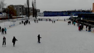 İnsanların buz pateni yaptığı kış paten pistinin insansız hava aracı görüntüsü. İnsanlar Kuzey Avrupa 'da bir hokey stadyumunda kayıyorlar. Sumy şehrindeki buz pateni pistinde insanlar eğleniyor..