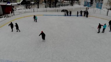 İnsanların buz pateni yaptığı kış paten pistinin insansız hava aracı görüntüsü. İnsanlar Kuzey Avrupa 'da bir hokey stadyumunda kayıyorlar. Sumy şehrindeki buz pateni pistinde insanlar eğleniyor..