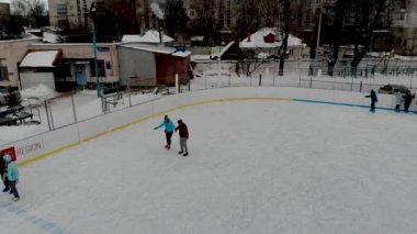 İnsanların buz pateni yaptığı kış paten pistinin insansız hava aracı görüntüsü. İnsanlar Kuzey Avrupa 'da bir hokey stadyumunda kayıyorlar. Sumy şehrindeki buz pateni pistinde insanlar eğleniyor..