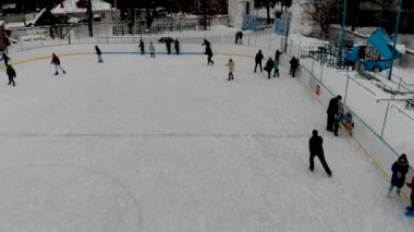 İnsanların buz pateni yaptığı kış paten pistinin insansız hava aracı görüntüsü. İnsanlar Kuzey Avrupa 'da bir hokey stadyumunda kayıyorlar. Sumy şehrindeki buz pateni pistinde insanlar eğleniyor..