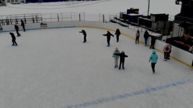 İnsanların buz pateni yaptığı kış paten pistinin insansız hava aracı görüntüsü. İnsanlar Kuzey Avrupa 'da bir hokey stadyumunda kayıyorlar. Sumy şehrindeki buz pateni pistinde insanlar eğleniyor..