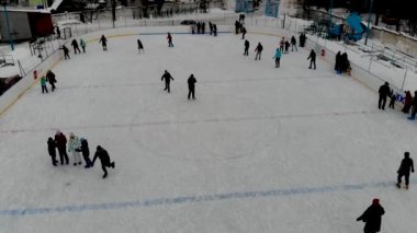 İnsanların buz pateni yaptığı kış paten pistinin insansız hava aracı görüntüsü. İnsanlar Kuzey Avrupa 'da bir hokey stadyumunda kayıyorlar. Sumy şehrindeki buz pateni pistinde insanlar eğleniyor..