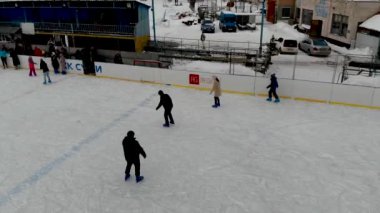 İnsanların buz pateni yaptığı kış paten pistinin insansız hava aracı görüntüsü. İnsanlar Kuzey Avrupa 'da bir hokey stadyumunda kayıyorlar. Sumy şehrindeki buz pateni pistinde insanlar eğleniyor..