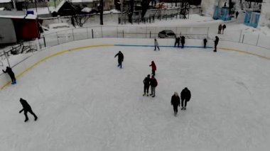 İnsanların buz pateni yaptığı kış paten pistinin insansız hava aracı görüntüsü. İnsanlar Kuzey Avrupa 'da bir hokey stadyumunda kayıyorlar. Sumy şehrindeki buz pateni pistinde insanlar eğleniyor..