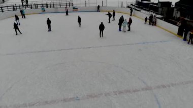 İnsanların buz pateni yaptığı kış paten pistinin insansız hava aracı görüntüsü. İnsanlar Kuzey Avrupa 'da bir hokey stadyumunda kayıyorlar. Sumy şehrindeki buz pateni pistinde insanlar eğleniyor..