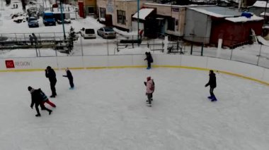 İnsanların buz pateni yaptığı kış paten pistinin insansız hava aracı görüntüsü. İnsanlar Kuzey Avrupa 'da bir hokey stadyumunda kayıyorlar. Sumy şehrindeki buz pateni pistinde insanlar eğleniyor..