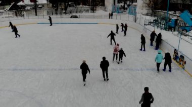İnsanların buz pateni yaptığı kış paten pistinin insansız hava aracı görüntüsü. İnsanlar Kuzey Avrupa 'da bir hokey stadyumunda kayıyorlar. Sumy şehrindeki buz pateni pistinde insanlar eğleniyor..
