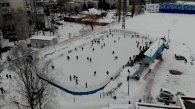 İnsanların buz pateni yaptığı kış paten pistinin insansız hava aracı görüntüsü. İnsanlar Kuzey Avrupa 'da bir hokey stadyumunda kayıyorlar. Sumy şehrindeki buz pateni pistinde insanlar eğleniyor..